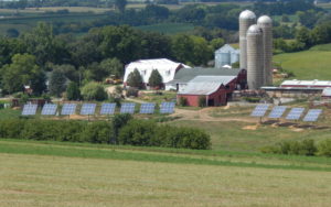 Farmhouse, barn, and grain silos with a row of 12 solar panels