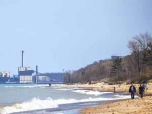 Beach-goers enjoy Indiana's Lake Michigan shore, alongside industrial buildings