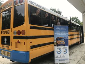 Smiling advocates enjoy a ride on an electric school bus