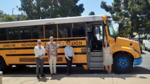 ELPC staff and partners stand in front of an electric school bus