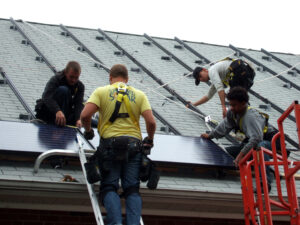 Four men install solar panels on a church roof in University Park, Maryland