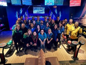 Group photo of ELPC staff in a bowling alley, wearing multicolored bowling shirts