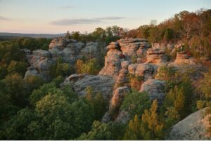 Rock formations are lit up by a setting sun, amid pine trees in Southern illinois Shawnee National Forest Garden of the Gods Wilderness Area