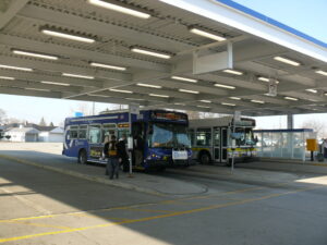 Pace buses pull into a depot while riders alight