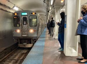 CTA blue line train pulls up to a subway station while riders wait to board
