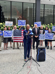 Congresswoman Kelly speaks in Chicago's federal plaza in front of a group of people holding an american flag and signs about climate change